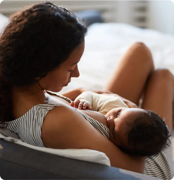 Maman allaitant son bébé sur un lit